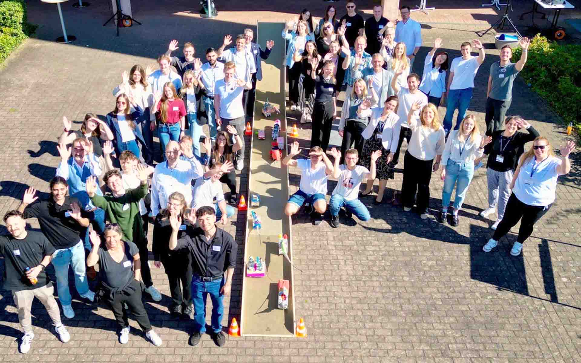 Gruppenfoto der Teilnehmenden am Connection Day mit winkenden Händen auf dem Hof