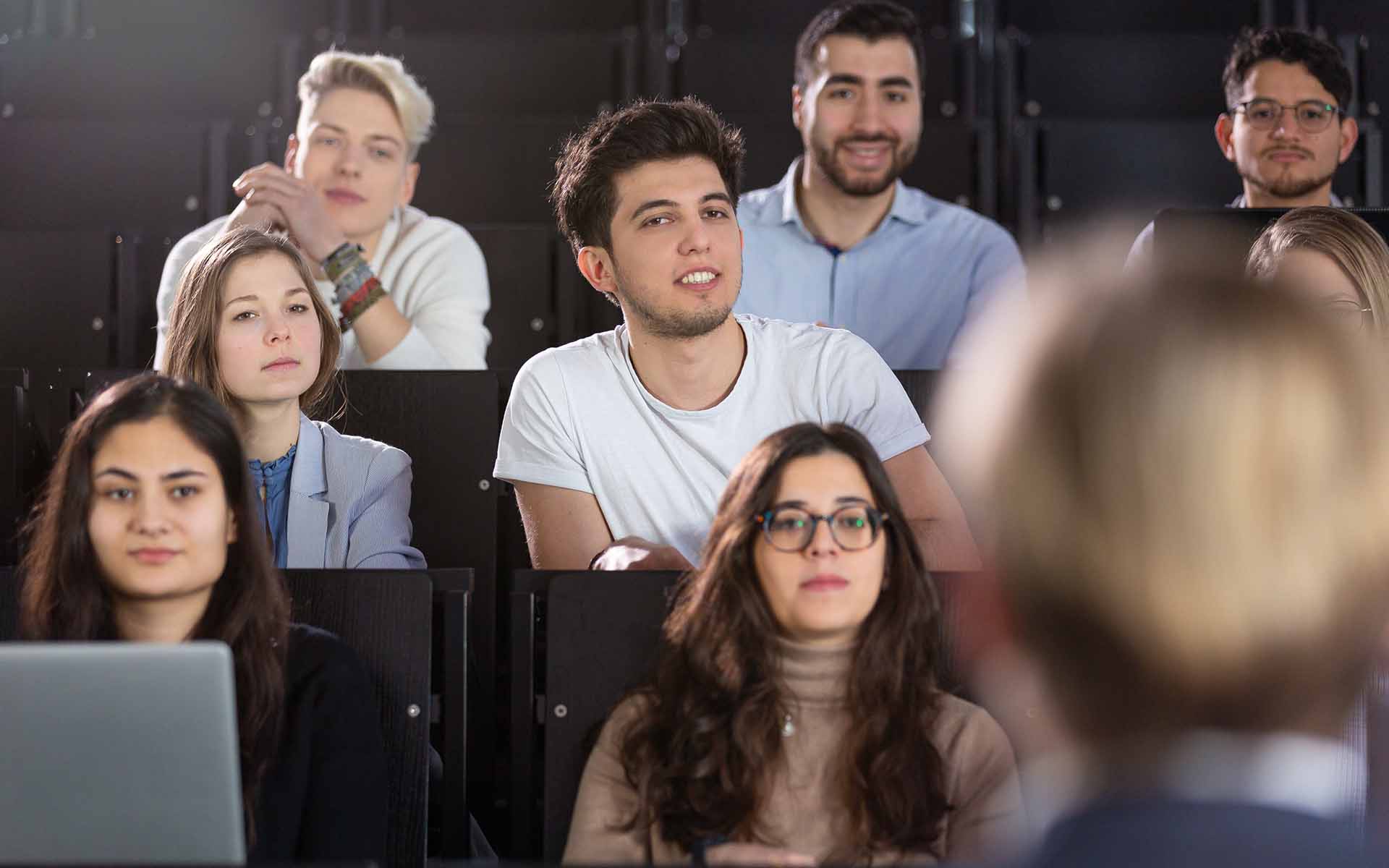Studierende sitzen im Hörsaal und hören Professorin zu